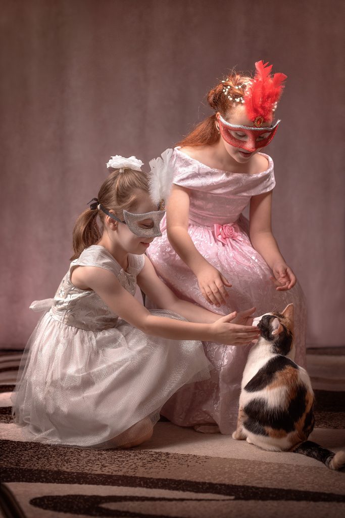Девочки играют с кошкой в розовых платьях