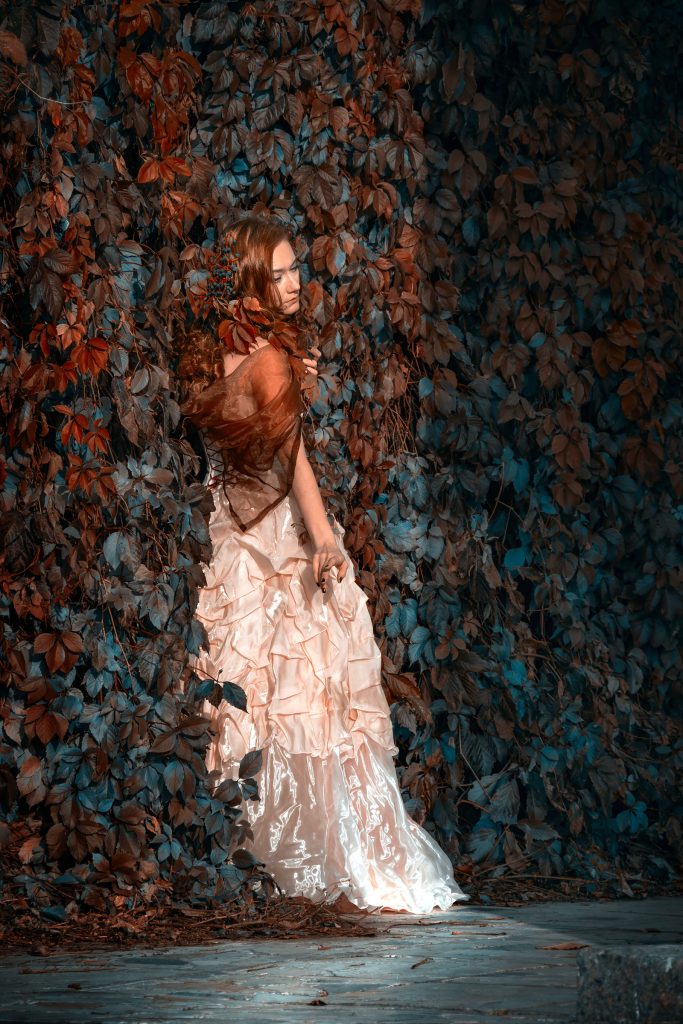 Девушка в светлом платье в красных листьях лозы дикого винограда