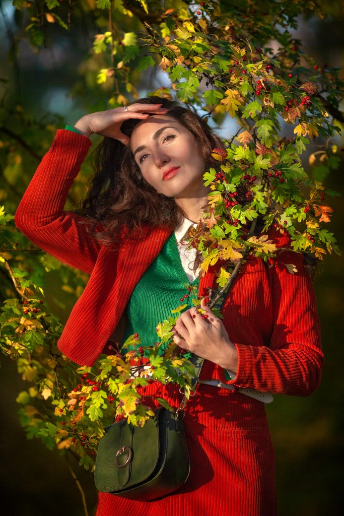 Девушка в красном мечтает в осеннем парке с живописной природой