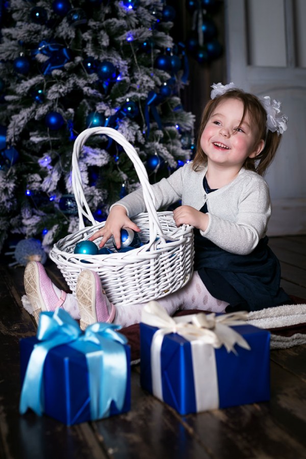 Девочка возле ёлки с новогодним подарком