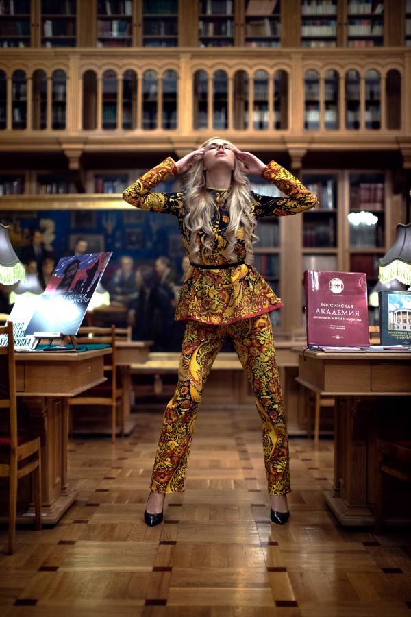Девушка в ярком костюме в библиотеке возле книг