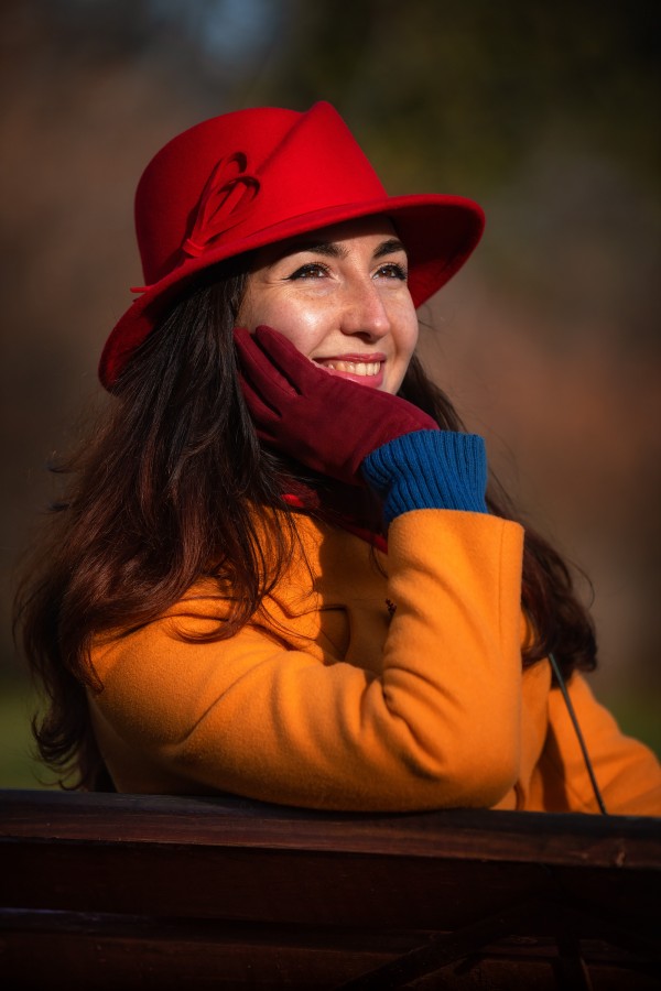 Девушка в красной шляпе радуется осеннему солнцу в парке