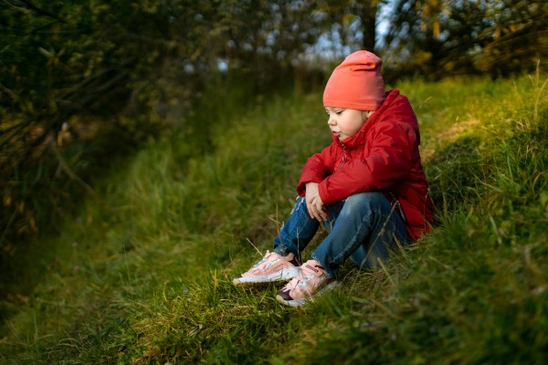 Девочка в красном сидит на траве