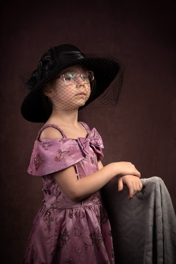 Девочка в розовом платье, очках и большой чёрной шляпе