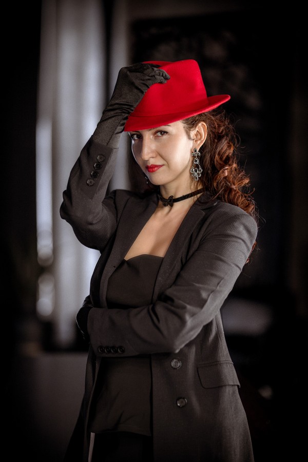 Девушка в красной шляпе и тёмном строгом костюме