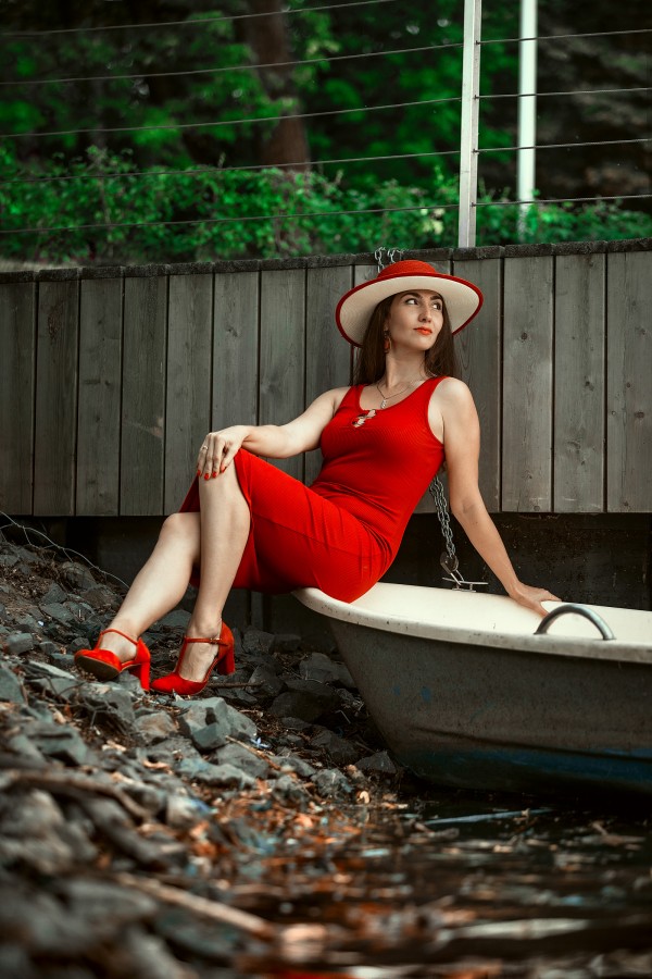 Девушка на лодке в красной шляпе мечтательно смотрит вдаль