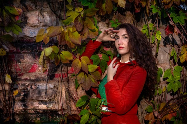 Элегантная девушка в красном костюме с мечтательным взглядом в осенней листве