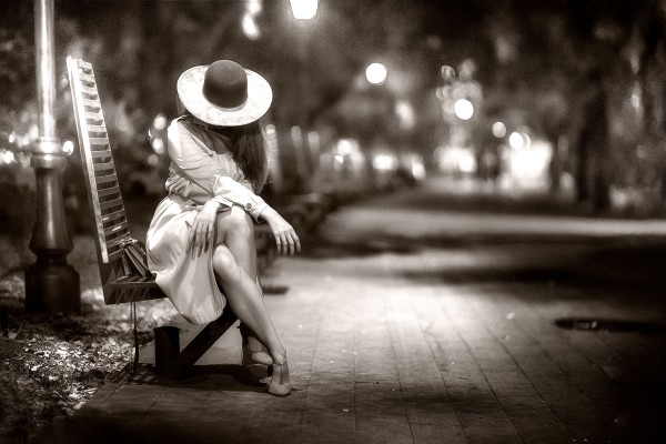 Девушка на лавочке в шляпе ночью. Черно-белое фото