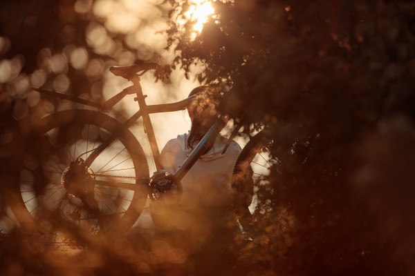 Девушка сидит в лучах солнца с велосипедом